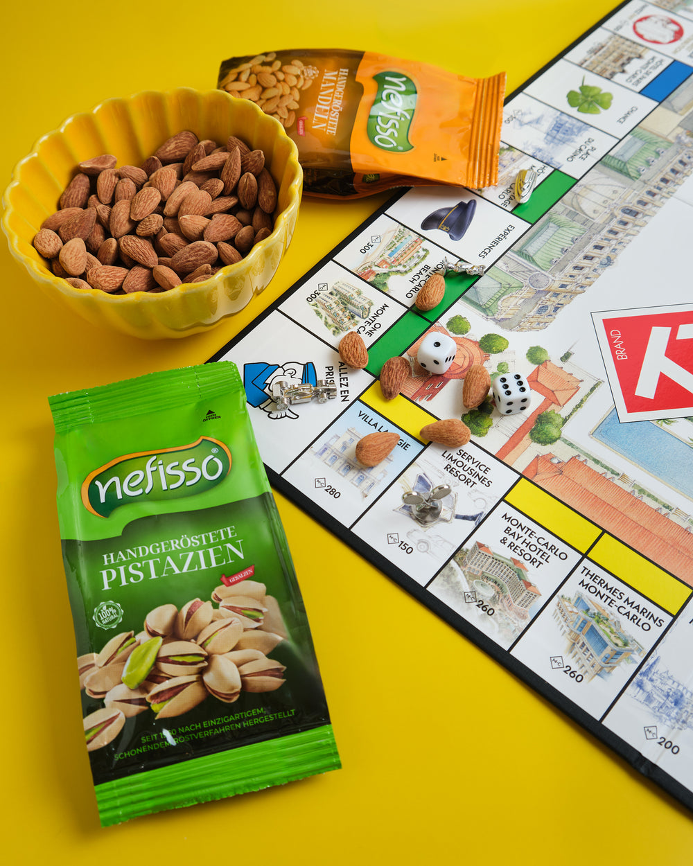 Nefisso Pistazien und Mandeln neben einer Schale Mandeln und einem Brettspiel