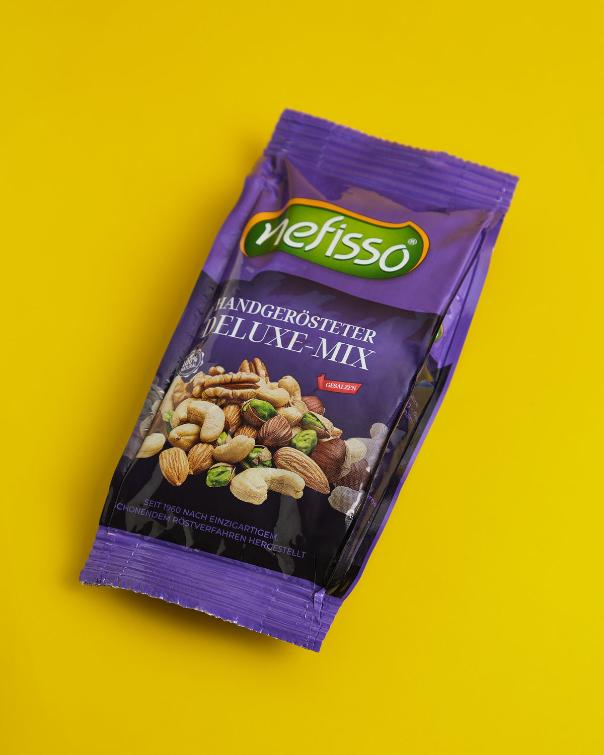 Echte Aufnahme einer violetten Nefisso Deluxe Mix Packung auf gelbem Hintergrund
