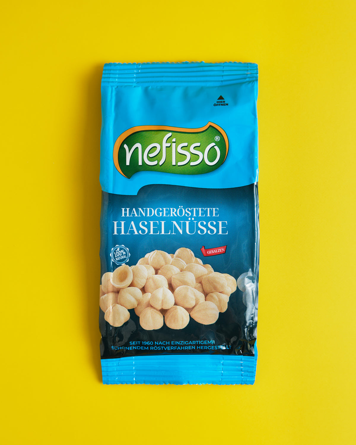 Echte Aufnahme einer blauen Nefisso Haselnusspackung auf gelbem Hintergrund