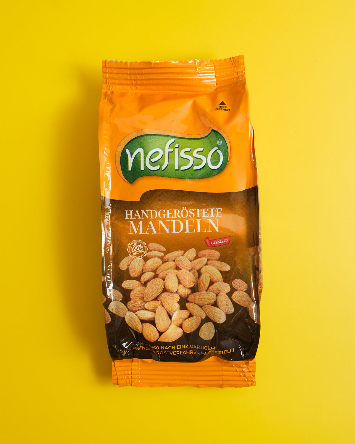 Echte Aufnahme einer orangefarbenen Nefisso Mandelpackung auf gelbem Hintergrund