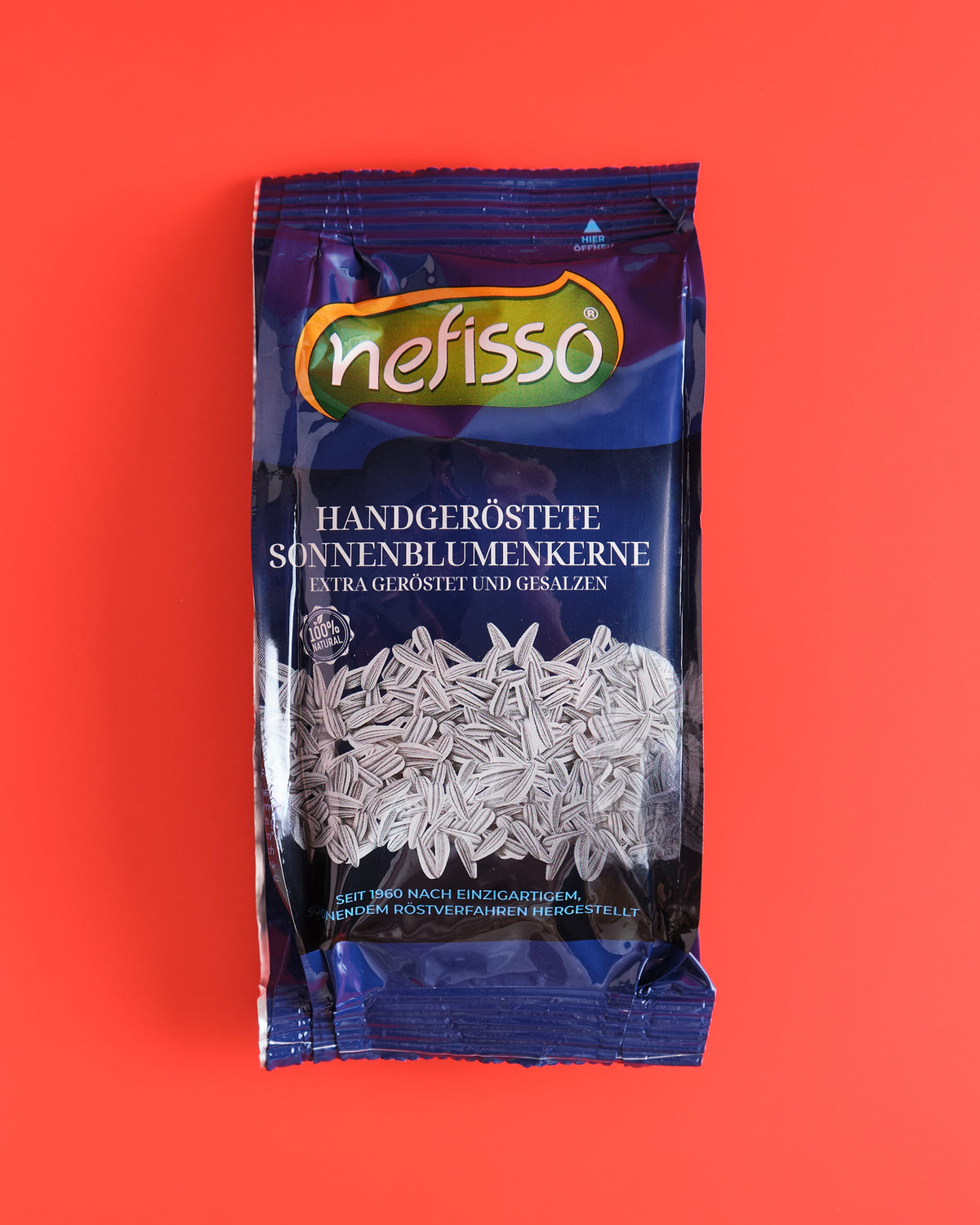 Nefisso Sonnenblumenkerne extra gesalzen in blauer Verpackung auf korallrotem Hintergrund